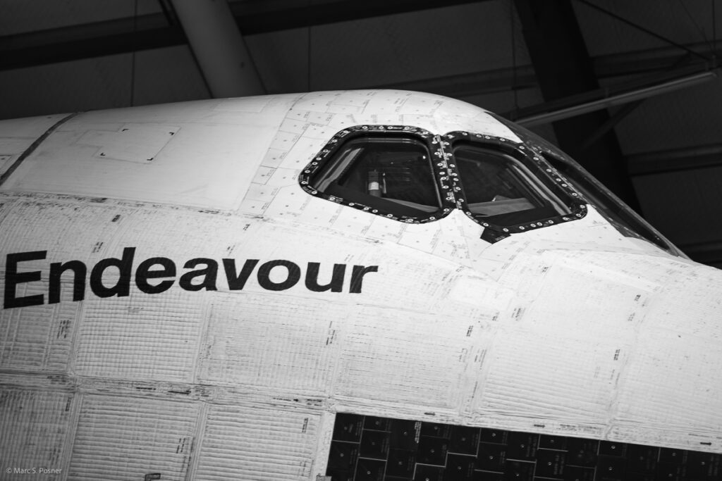 Photograph of space shuttle Endeavour showing the nameplate and the cockpit windows from the right side of the orbiter.
