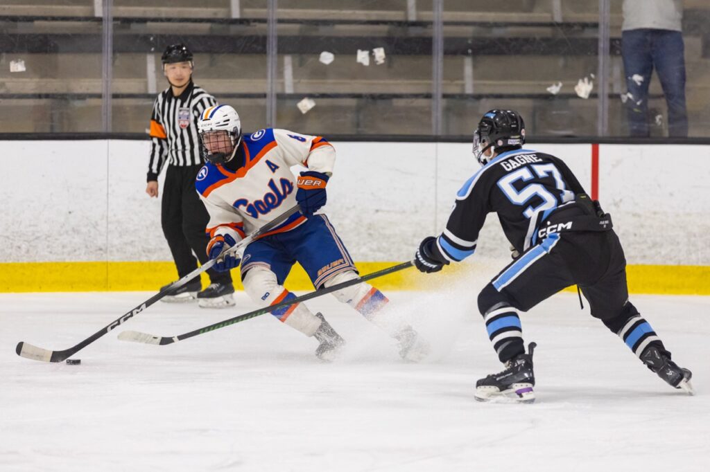an ice hockey player sprays ice as he cuts to skate past an opponent