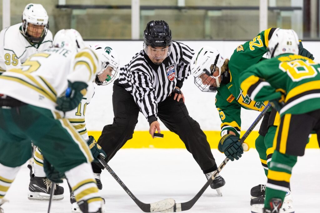 a hockey referee drops the puck for a face-off