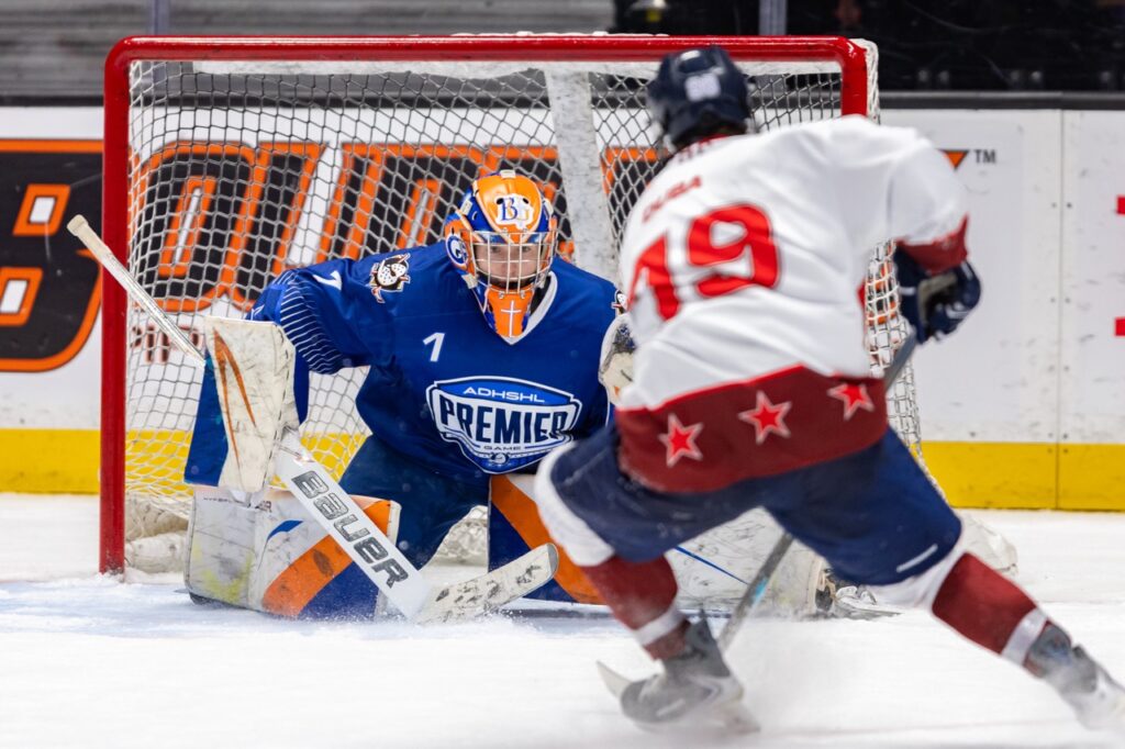 an ice hockey goalie prepares to make a save against a opponent on a break away