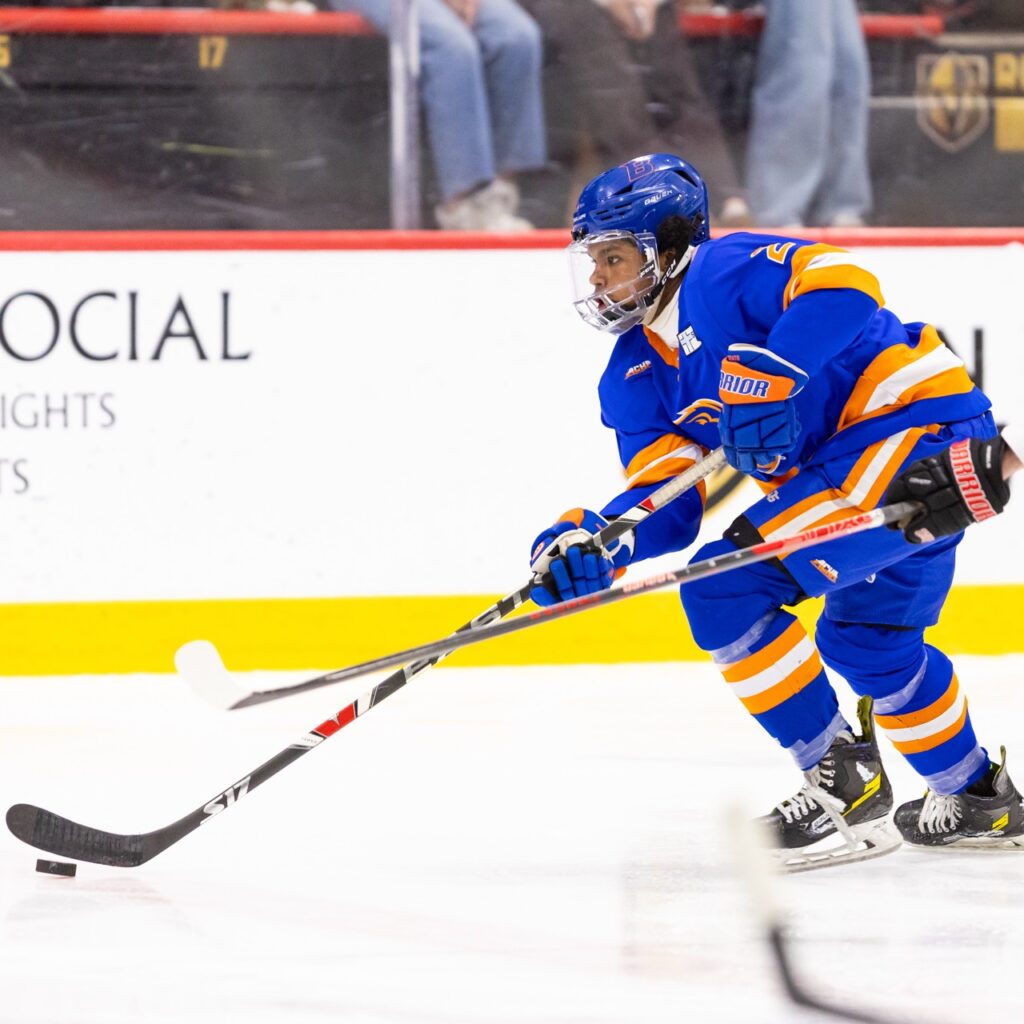 A hockey player skates with the puck
