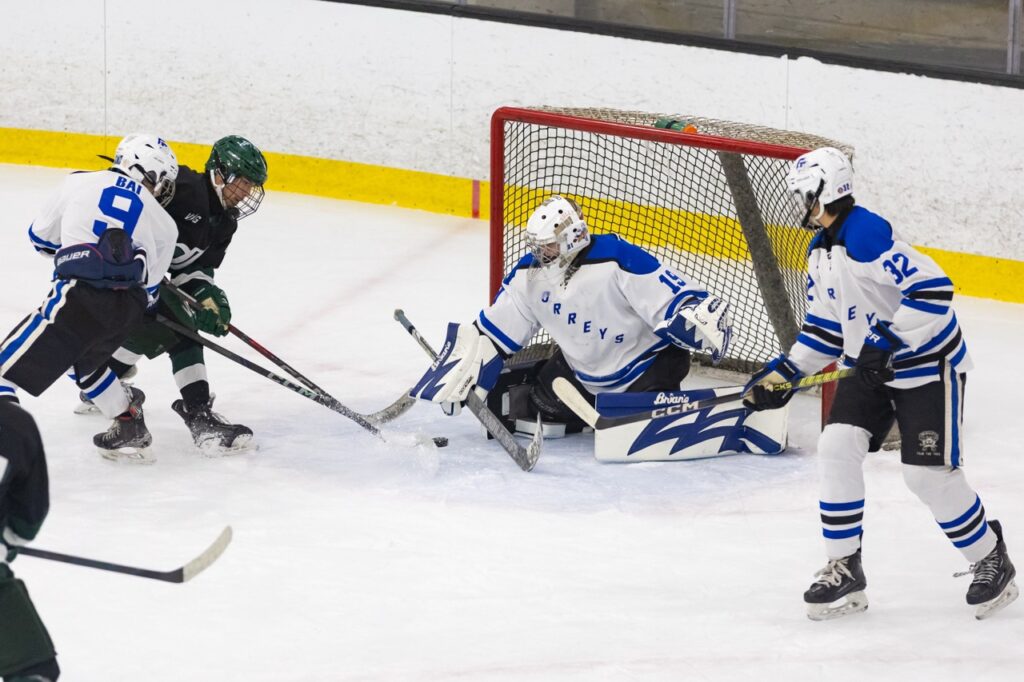 an ice hockey goalie makes a save against an opponent