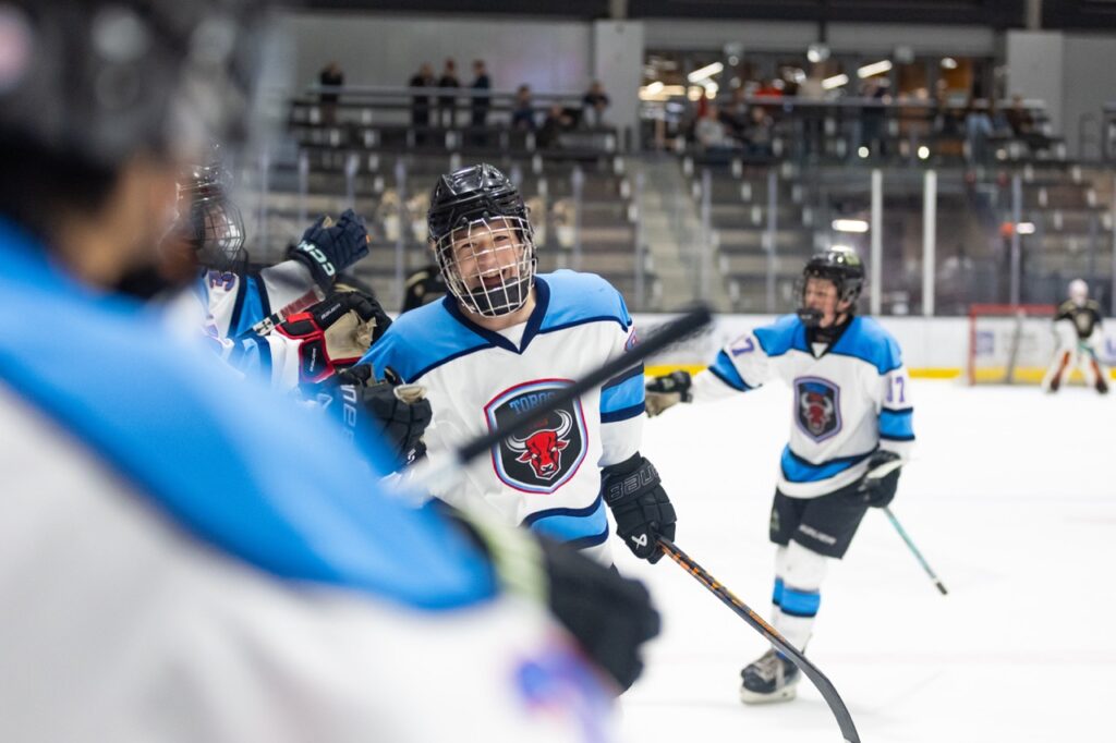 a hockey player bumps fists with teammates on the bench to celebrate a goal