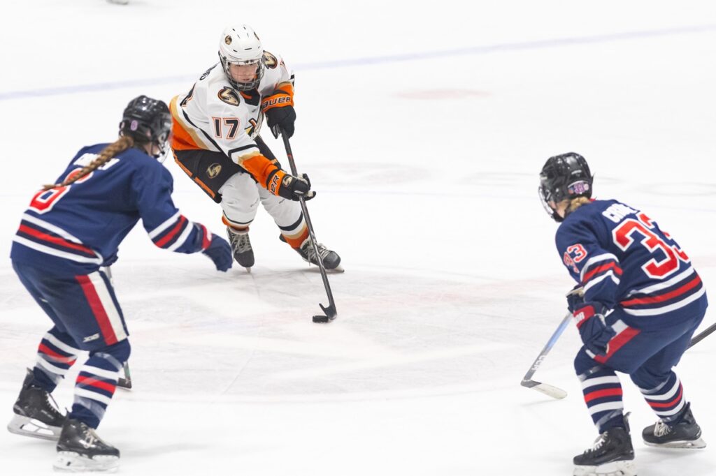 An ice hockey player skates with the puck