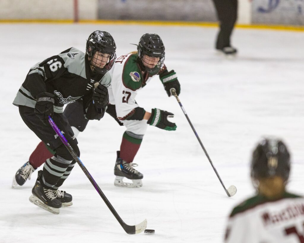 An ice hockey player skates with the puck