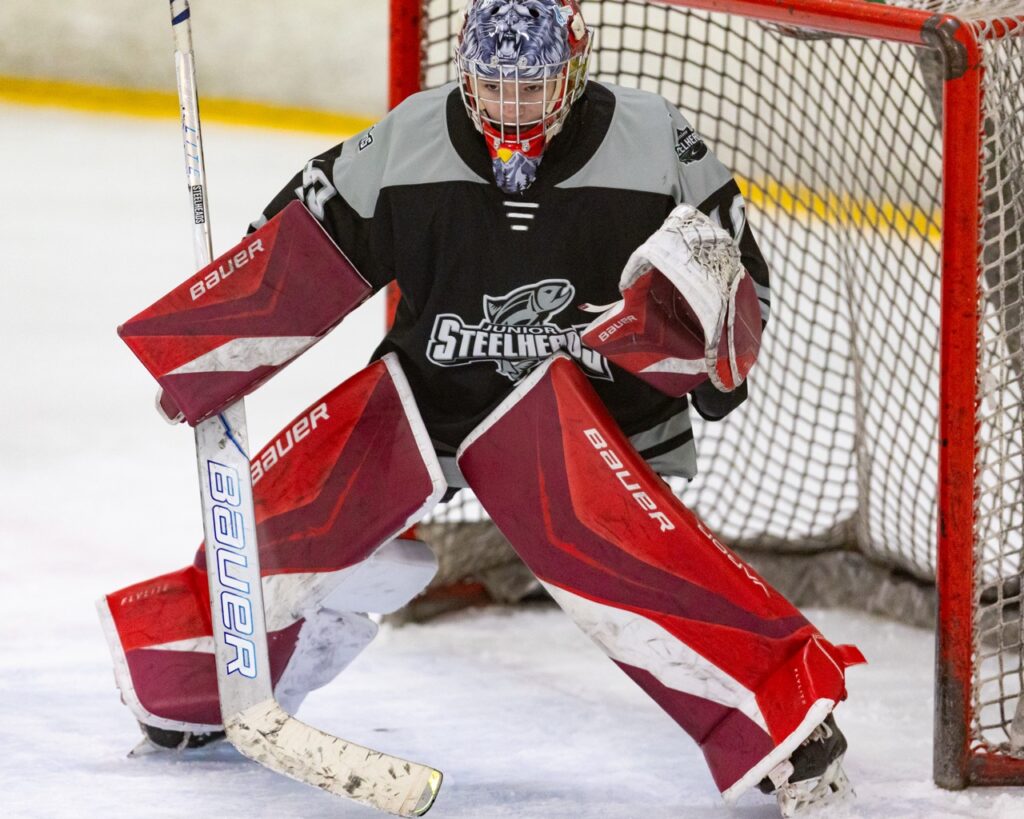 An ice hockey goalie tracks the puck.